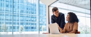 Busy manager consulting employee using laptop computer working in office.
